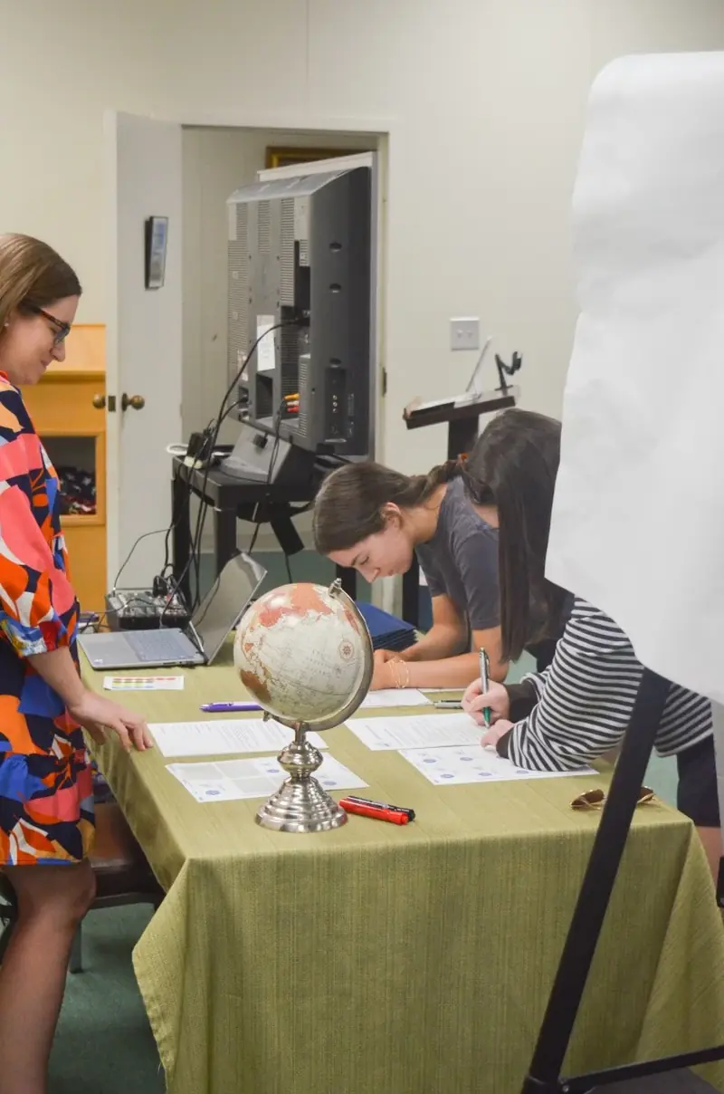 Students filling out worksheets at a table with a globe centerpiece