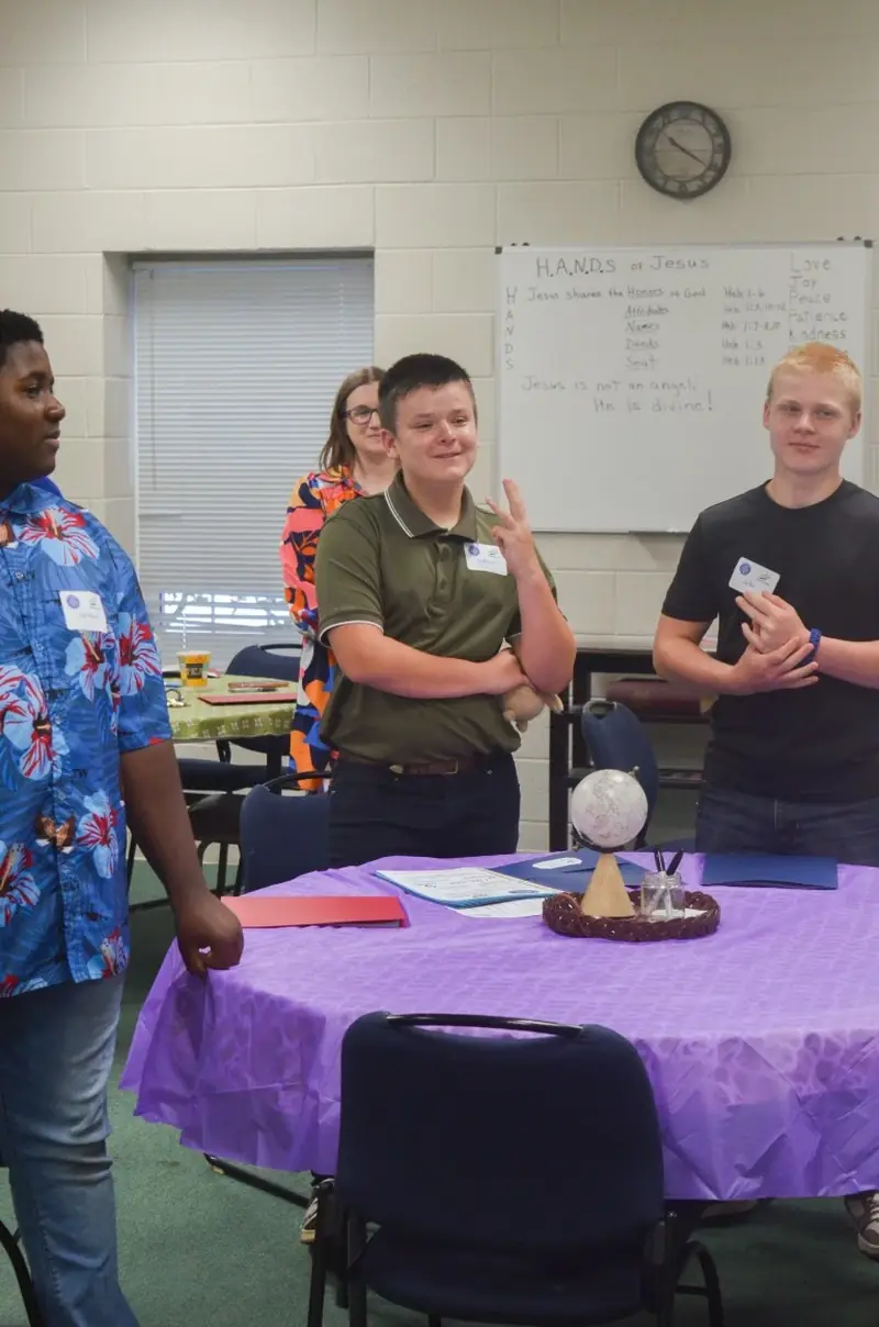 Three students standing together at their table during a group activity